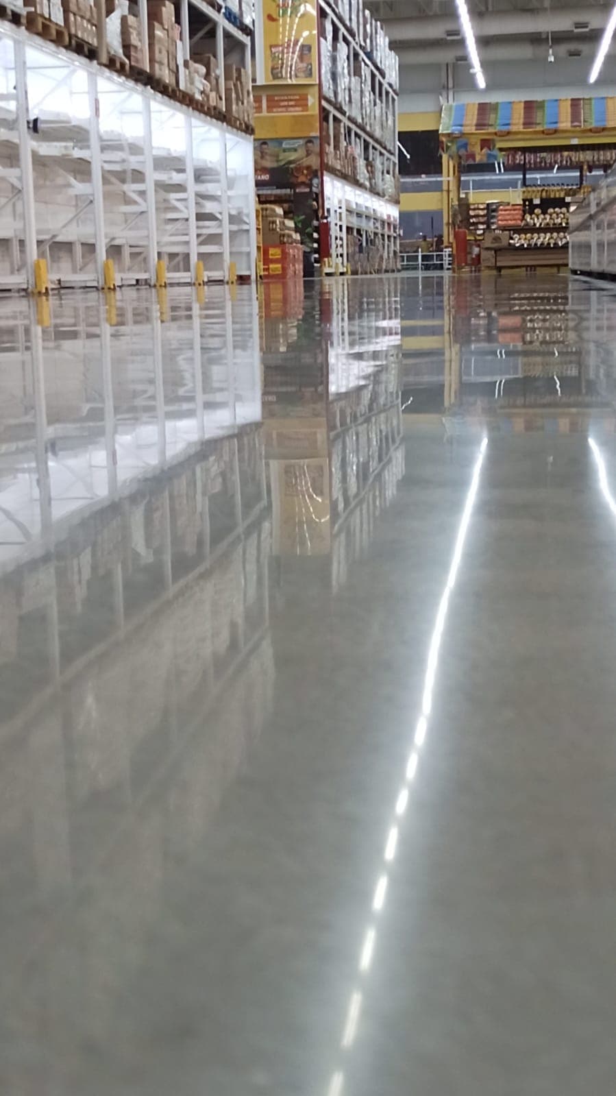 Corredor de armazém com a linha de luminárias LED refletida no piso